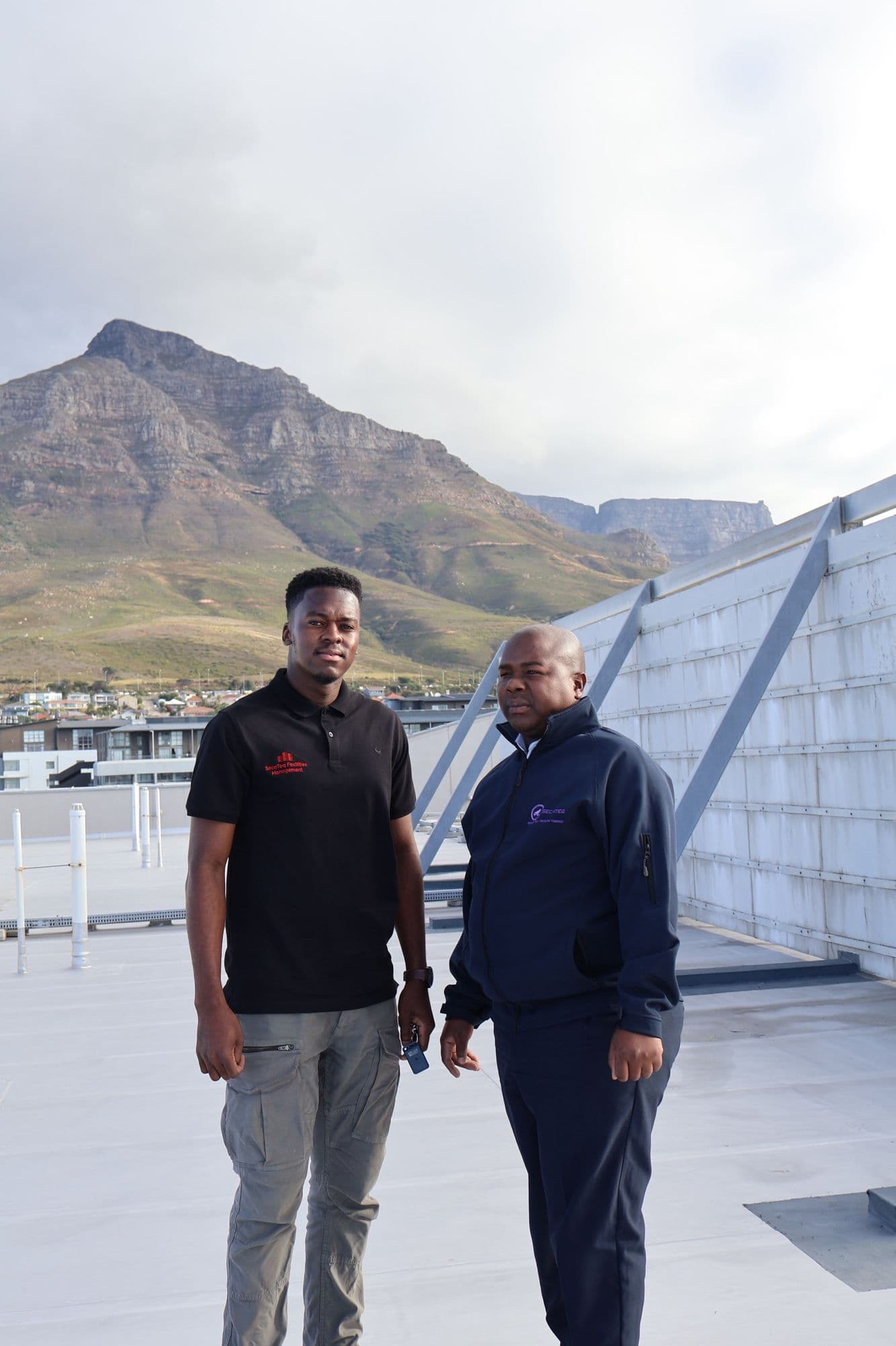 A SecaTeq FM technician and a SecaTeq officer on a Cape Town rooftop with Devil's Peak behind them