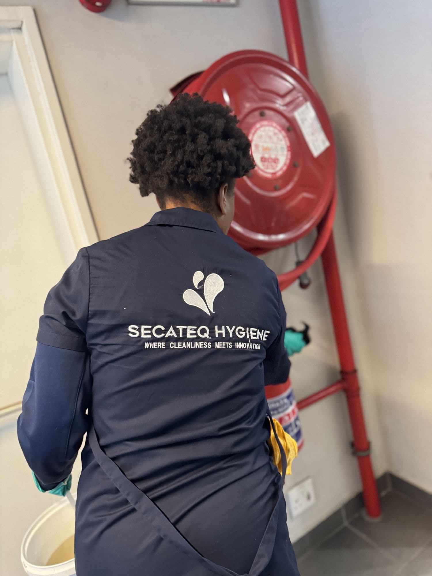 A SecaTeq Hygiene team member cleaning beside a fire hose reel