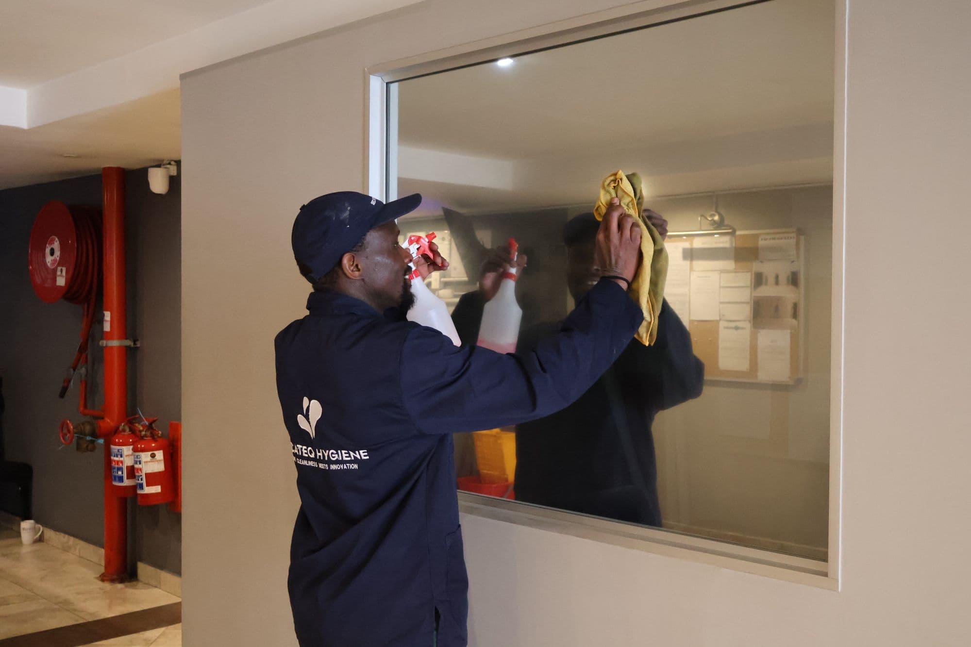 A SecaTeq Hygiene team member cleaning a mirror in a building corridor